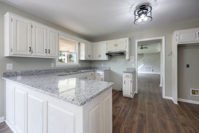 kitchen featuring white cabinets, dark hardwood / wood-style floors, light stone countertops, and kitchen peninsula