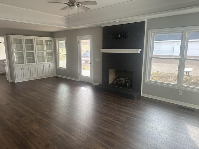 unfurnished living room featuring dark hardwood / wood-style floors, a brick fireplace, and a wealth of natural light