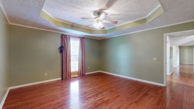 spare room with a tray ceiling, ceiling fan, hardwood / wood-style flooring, and crown molding