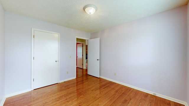 unfurnished bedroom with light hardwood / wood-style flooring and a textured ceiling