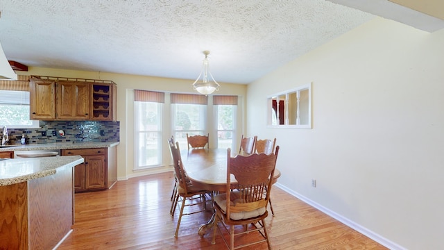 dining room featuring light wood-type flooring, a textured ceiling, and sink