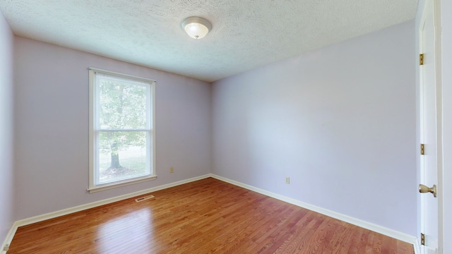 unfurnished room featuring wood-type flooring and a textured ceiling