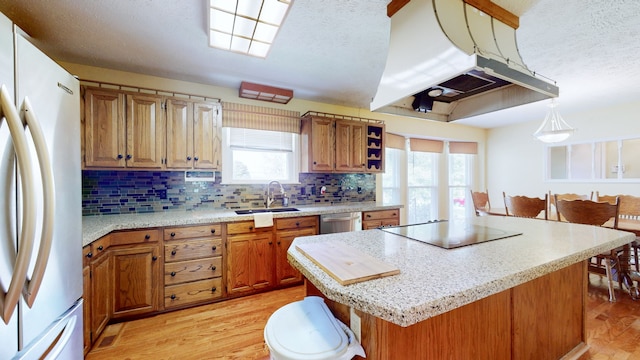 kitchen with black electric stovetop, white refrigerator, a center island, sink, and island range hood