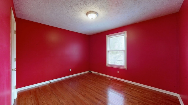 empty room with a textured ceiling and wood-type flooring