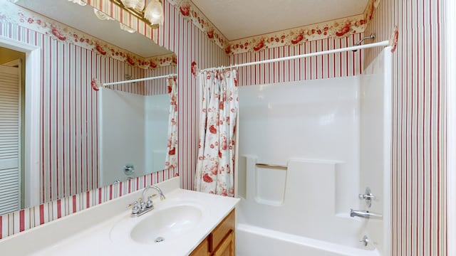 bathroom with shower / bathtub combination with curtain, a textured ceiling, and vanity