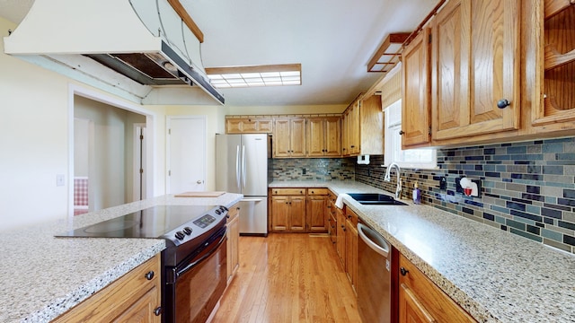 kitchen with light stone counters, sink, light hardwood / wood-style flooring, stainless steel appliances, and decorative backsplash