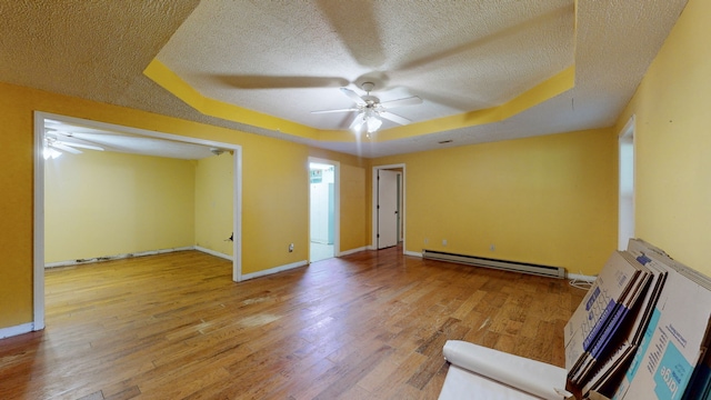 interior space featuring a textured ceiling, hardwood / wood-style floors, baseboard heating, and ceiling fan