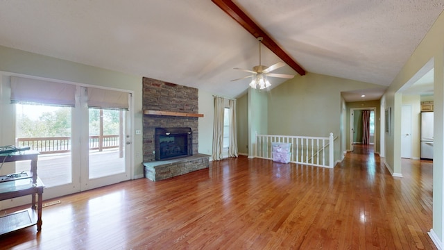 unfurnished living room with wood-type flooring, vaulted ceiling with beams, a fireplace, and ceiling fan