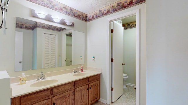 bathroom featuring a textured ceiling, vanity, and toilet