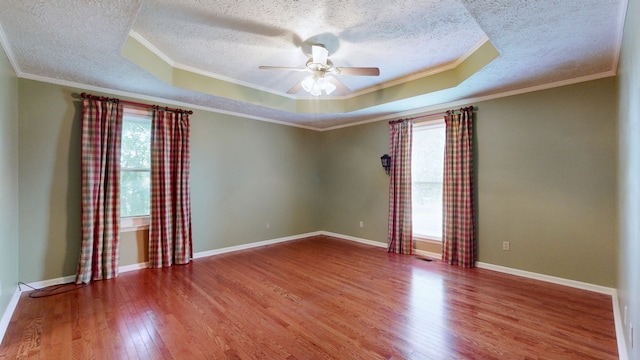 unfurnished room with a wealth of natural light, a tray ceiling, and hardwood / wood-style floors