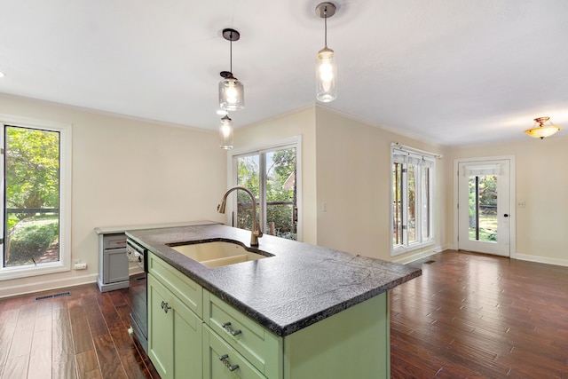 kitchen with pendant lighting, sink, green cabinets, dark wood-type flooring, and a center island with sink