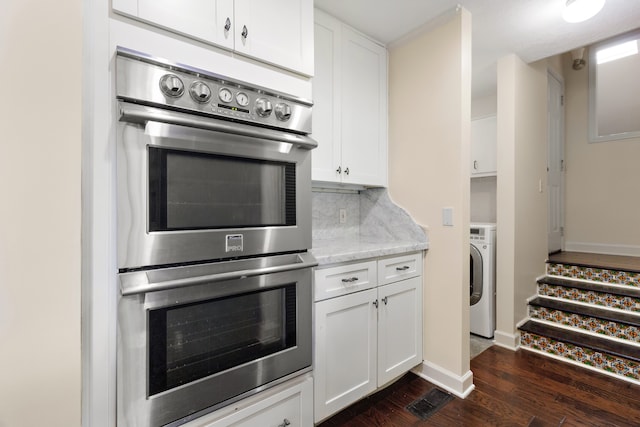 kitchen featuring washer / clothes dryer, white cabinets, and double oven