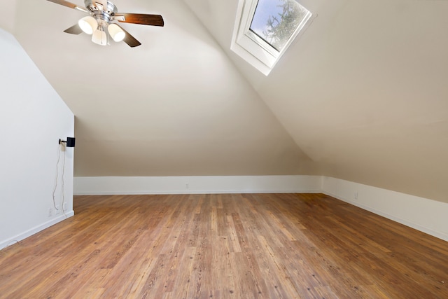 additional living space with lofted ceiling with skylight, ceiling fan, and light wood-type flooring