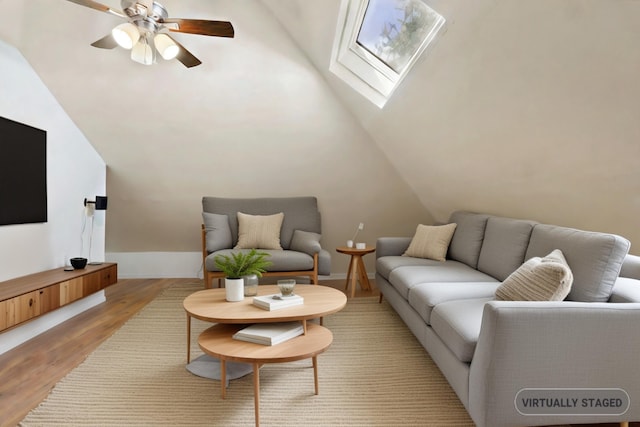 living room with light hardwood / wood-style flooring, lofted ceiling with skylight, and ceiling fan