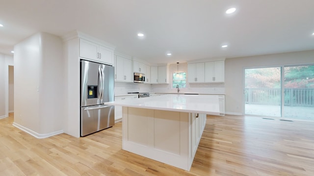 kitchen with light hardwood / wood-style flooring, white cabinets, a center island, and appliances with stainless steel finishes