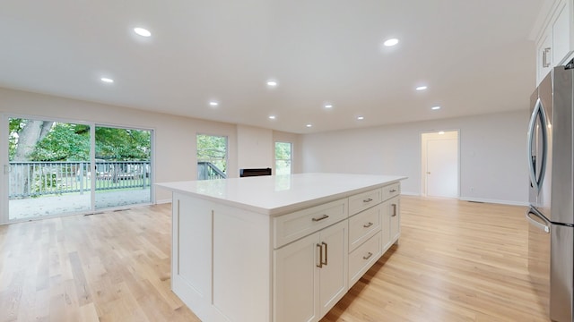 kitchen with light hardwood / wood-style flooring, white cabinetry, a kitchen island, and stainless steel fridge