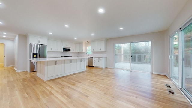 kitchen with a kitchen island, white cabinetry, light hardwood / wood-style flooring, and stainless steel appliances