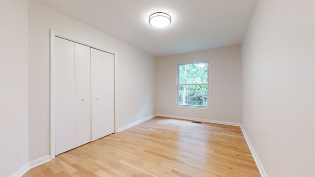 unfurnished bedroom featuring light hardwood / wood-style floors and a closet