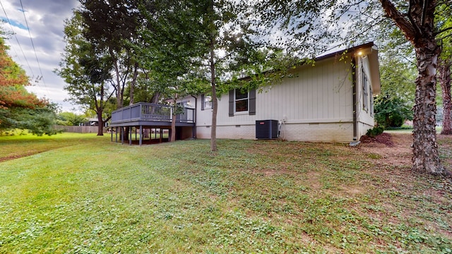 rear view of house featuring a lawn, a wooden deck, and central AC