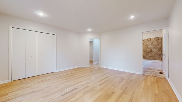 unfurnished bedroom with connected bathroom, light hardwood / wood-style floors, and a closet