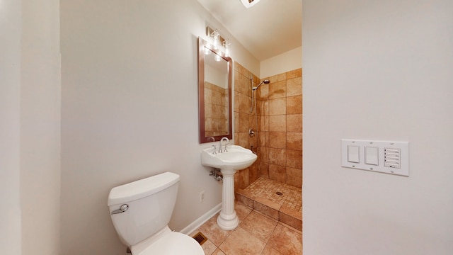 bathroom featuring a tile shower, toilet, and tile patterned floors