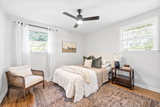 bedroom with multiple windows, wood-type flooring, and ceiling fan