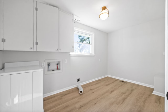 clothes washing area with washer / clothes dryer, light hardwood / wood-style flooring, and cabinets