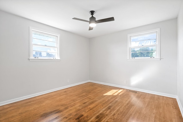 spare room featuring wood-type flooring, ceiling fan, and plenty of natural light