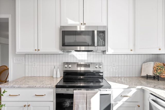 kitchen with light stone countertops, stainless steel appliances, white cabinets, and decorative backsplash