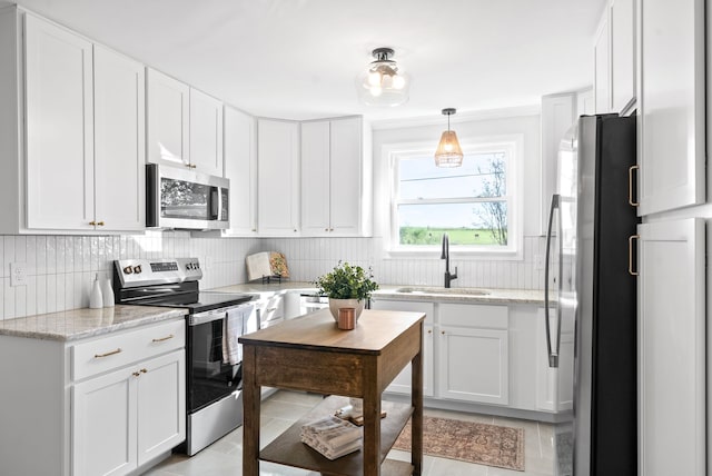 kitchen featuring sink, light tile patterned floors, stainless steel appliances, and white cabinets