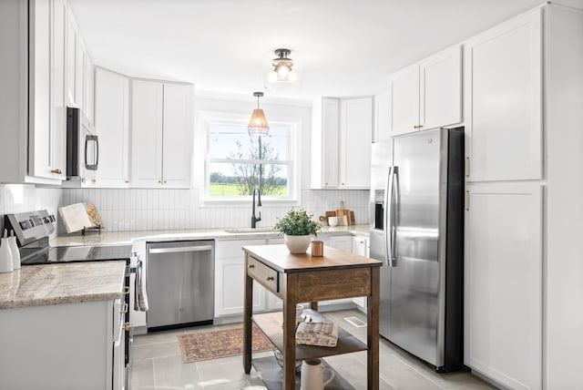 kitchen featuring light stone counters, sink, white cabinets, appliances with stainless steel finishes, and decorative light fixtures