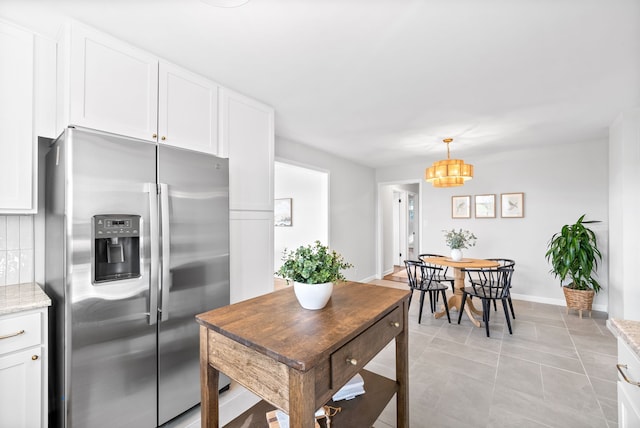 kitchen featuring pendant lighting, light tile patterned flooring, white cabinets, stainless steel refrigerator with ice dispenser, and light stone countertops