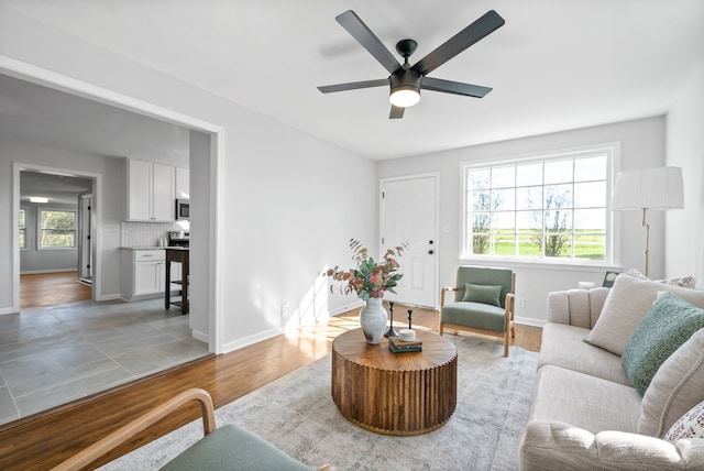 living room with light wood-type flooring, ceiling fan, and plenty of natural light