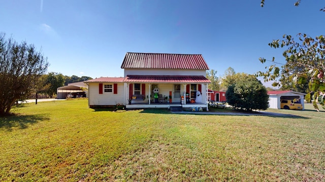 back of house with covered porch, an outbuilding, and a yard