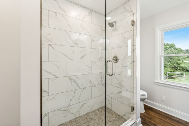 bathroom featuring wood-type flooring, plenty of natural light, toilet, and an enclosed shower