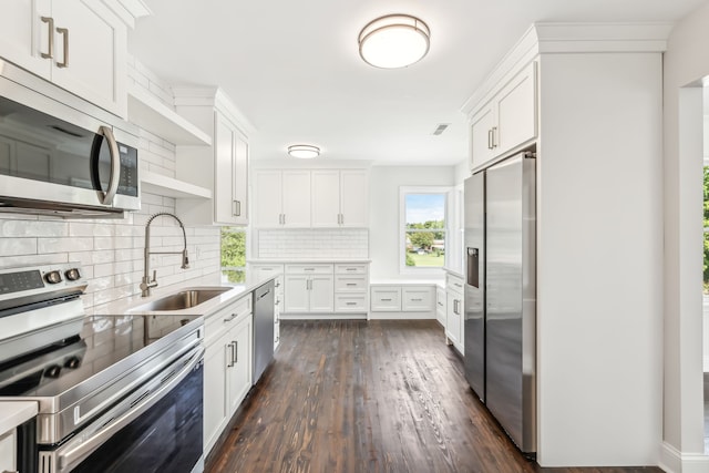 kitchen with appliances with stainless steel finishes, dark wood-type flooring, tasteful backsplash, white cabinets, and sink