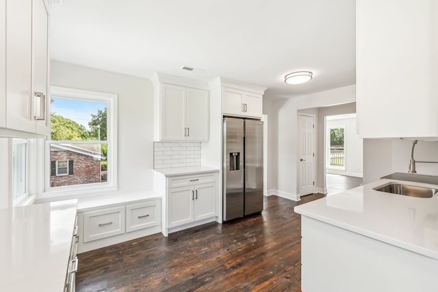 kitchen with stainless steel refrigerator with ice dispenser, plenty of natural light, and white cabinets