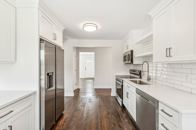 kitchen with appliances with stainless steel finishes, white cabinetry, dark wood-type flooring, backsplash, and sink