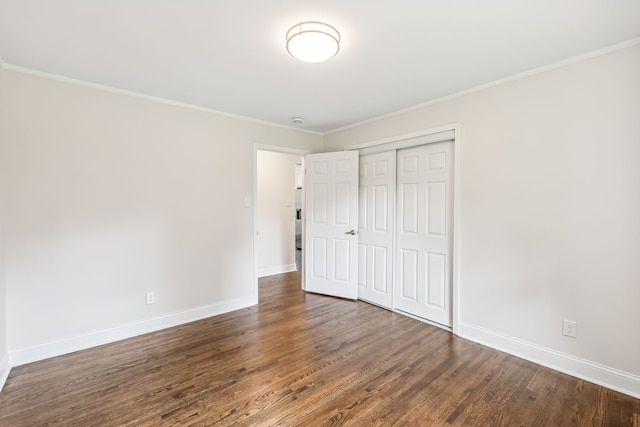 unfurnished bedroom featuring a closet, dark hardwood / wood-style floors, and crown molding