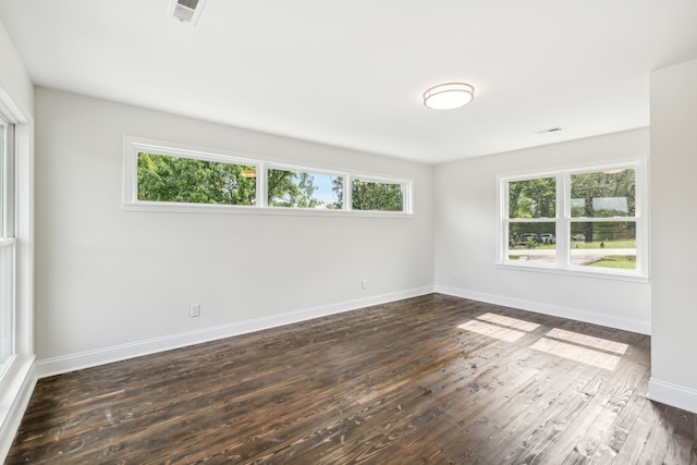 spare room featuring dark hardwood / wood-style floors and a healthy amount of sunlight