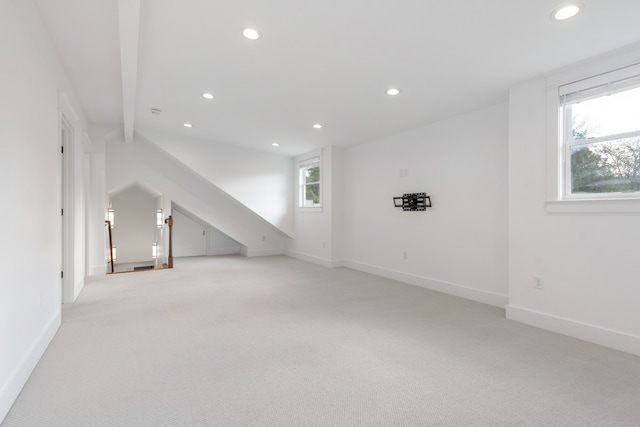 bonus room with beam ceiling, light colored carpet, and a healthy amount of sunlight