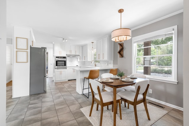 tiled dining area featuring crown molding and sink