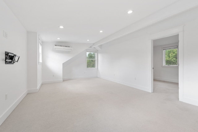 unfurnished room featuring an AC wall unit, light colored carpet, and a wealth of natural light