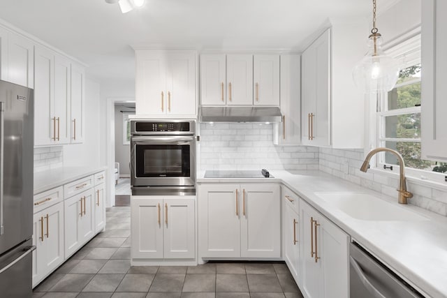 kitchen with pendant lighting, stainless steel appliances, white cabinets, and sink