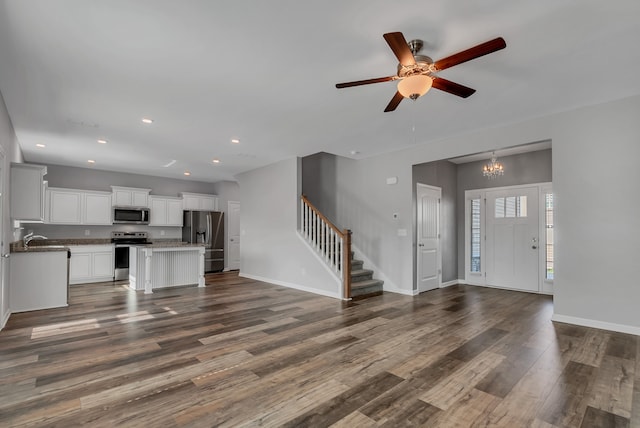 kitchen featuring dark wood-type flooring, white cabinets, ceiling fan with notable chandelier, stainless steel appliances, and a center island