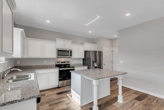 kitchen with white cabinets, sink, a kitchen island, wood-type flooring, and stainless steel appliances