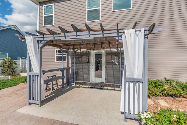 view of exterior entry featuring a pergola and a patio