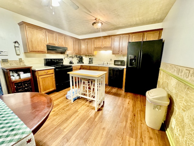 kitchen with ceiling fan, a textured ceiling, light hardwood / wood-style flooring, and black appliances