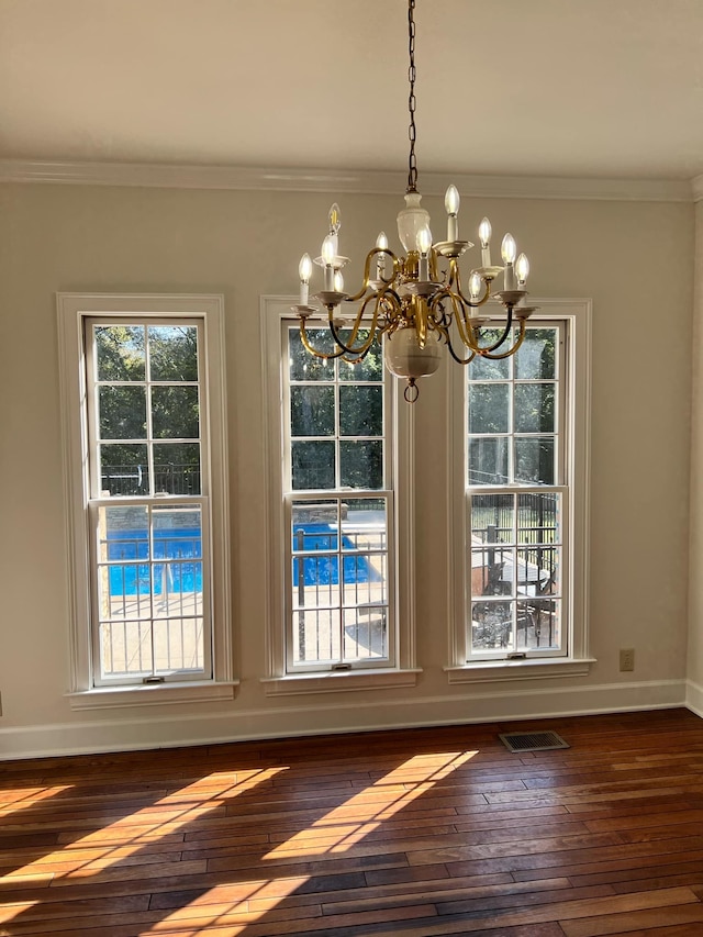 unfurnished dining area with a notable chandelier, dark hardwood / wood-style floors, and ornamental molding