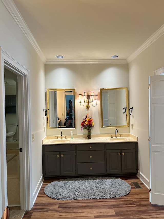 bathroom with crown molding, vanity, and hardwood / wood-style flooring